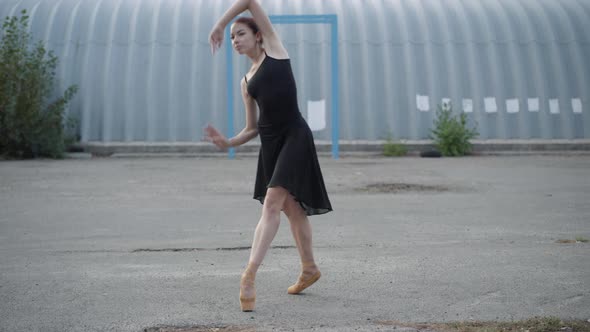 Camera Approaches To Slim Young Ballerina Dancing on Tiptoes on Urban Wasteland