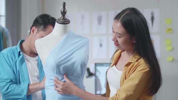 Asian Male And Female Designers Wearing Fabric On A Mannequin While Designing Clothes