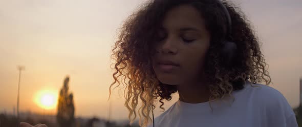 Video of African young woman in headphones dancing outdoors.  Shot with RED helium camera in 8K.