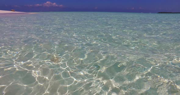 Daytime flying travel shot of a sunshine white sandy paradise beach and aqua turquoise water backgro