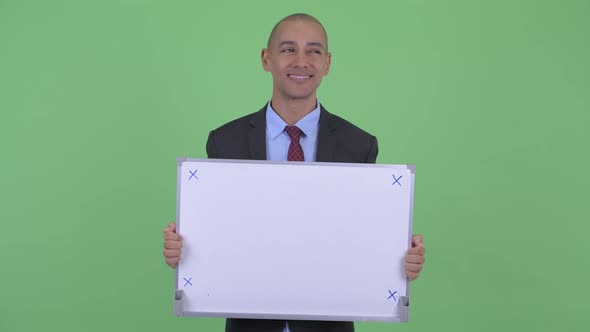 Happy Bald Multi Ethnic Businessman Thinking and Talking While Holding White Board