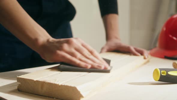 Woman Builder Sanding Wooden Board with Sandpaper