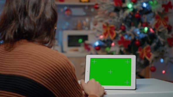 Young Woman Sitting at Home with Green Screen Display