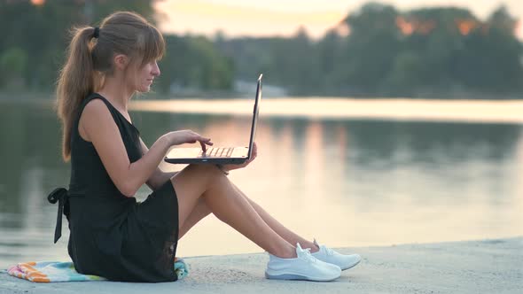 Young Woman Working Behind Laptop Sitting in Summer Park Outdoors