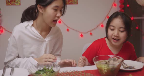 Happy Chinese Family Eating Dinner For Chinese New Year Celebrations Together At Home.