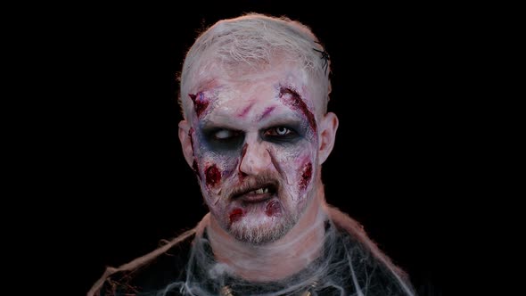 Sinister Man in Costume of Halloween Crazy Zombie with Bloody Wounded Scars Face Trying to Scare