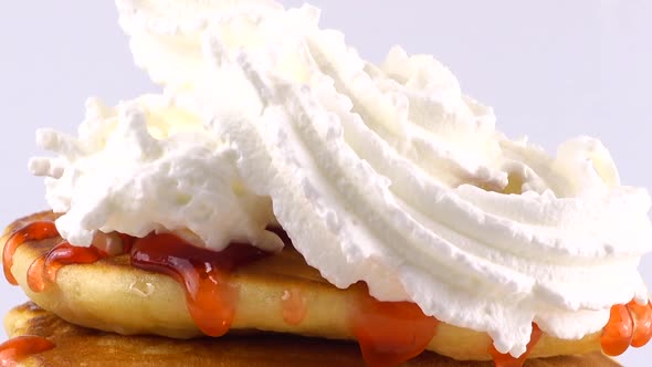 American pancakes with strawberry topping and whipped cream on a white background.