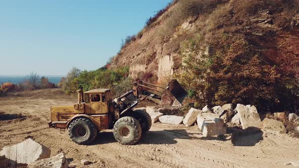 Bulldozer is Working Near Sand Quarry on the Background of Stones