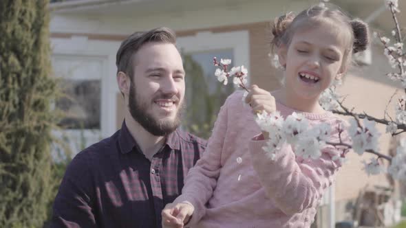 Portrait Young Bearded Father Lifting His Little Smiling Daughter so She Could Smell the Tree