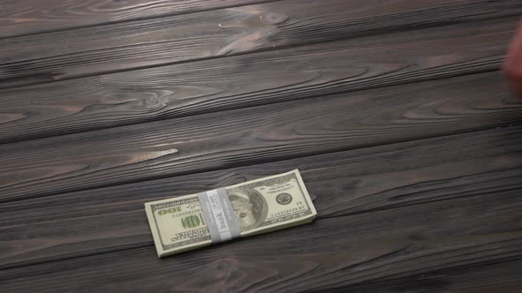 Bundle of Dollars Falling on Wooden Table