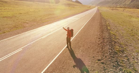 Flight Over Hitchhiker Tourist Walking on Asphalt Road