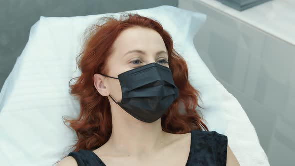 A Woman in the Hospital Is Lying on a Couch in a Medical Mask and Talking To a Doctor