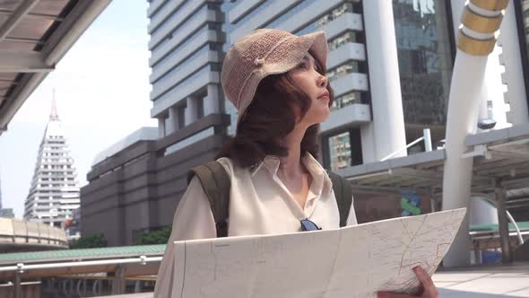 young Asian backpacker woman direction and looking on location map while traveling at Bangkok.