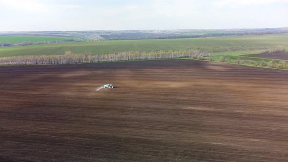 Aerial scenic of a tractor spraying on land field