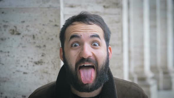 funny, witty man doing the tongue at camera- outdoor