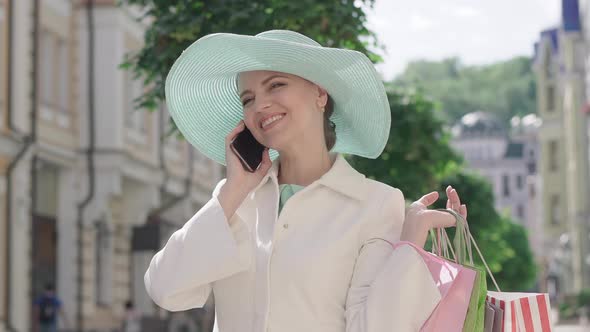 Portrait of Happy Excited Woman Talking on the Phone on Sunny City Street. Beautiful Brunette