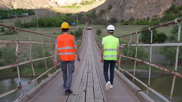 Engineer and Worker Investigate Suspension Bridge