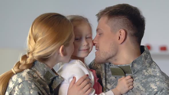 Young Parents in Camouflage Uniform Kissing Daughter Cheek, Family Closeness