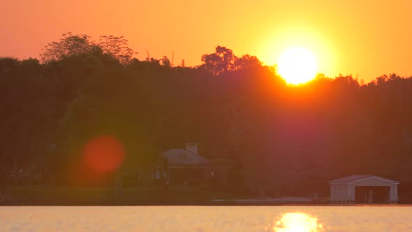 A young woman sup stand-up paddleboarding on a lake at sunset.