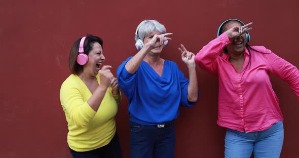 Mature women dancing in the city to music playlist with wireless heaphones