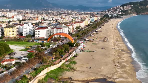 Aerial drone view of parachute jumper flying over beautiful Alanya