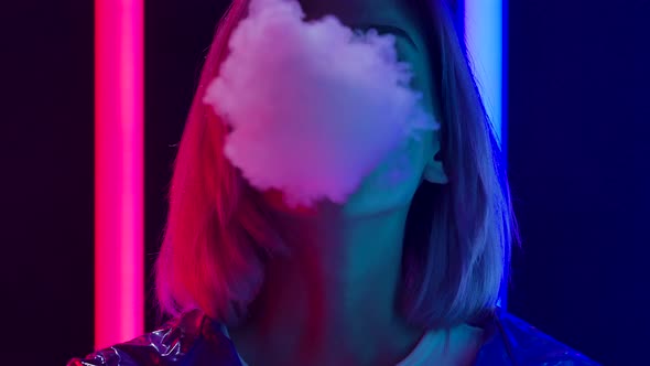 Portrait of a Young Stylish Woman Smokes Hookah and Blows White Smoke Directly Into the Camera