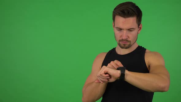 A Young Handsome Athlete Works on a Touchscreen Wristwatch - Green Screen Studio