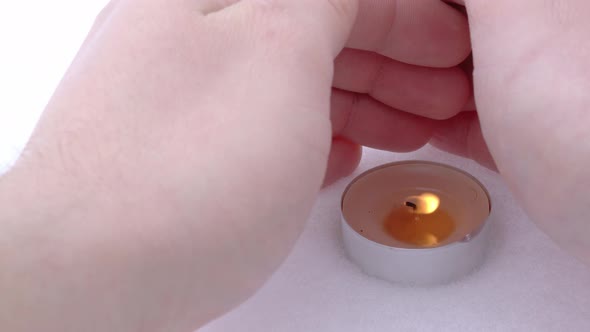 An Attempt to Protect the Fire of a Candle From the Wind By Covering It with your Hands in Winter in