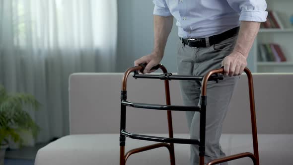 Male handicapped trying to move with walking frame at hospital, rehabilitation