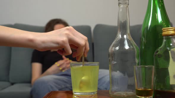 a woman suffers from a hangover, she drinks painkillers in a glass of water