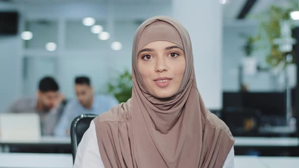 Smiling Arab Muslim Woman in Hijab Corporate Employee Giving an Interview Talk Looking at Camera