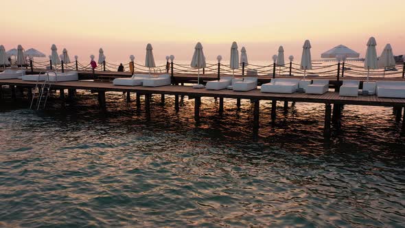 Wooden Bridge with Sunbeds in the Sea at Sunset