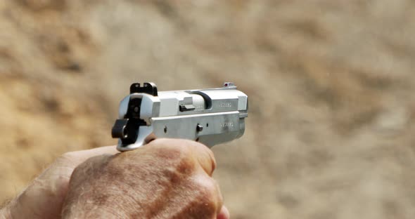 Slow motion of a hand gun firing in a firing range with cartridge flying away