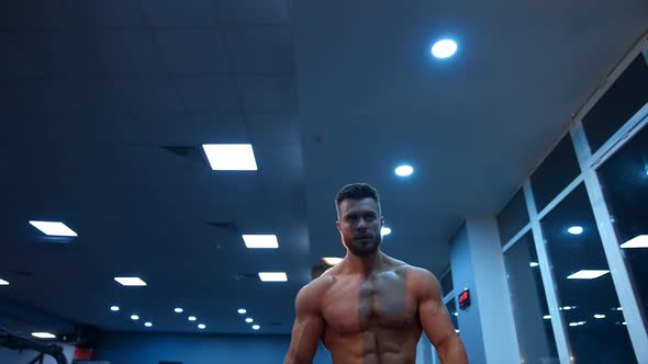 Shirtless male athlete walks to the horizontal bar for training. Selective focus on bodybuilder.