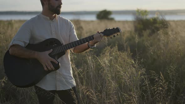 Spanish Guitarist Performing in the Grassy Field in Autumn Playing Chords and Singing Song on Black