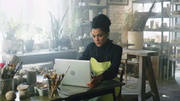 Woman Potter Opens Laptop to Work