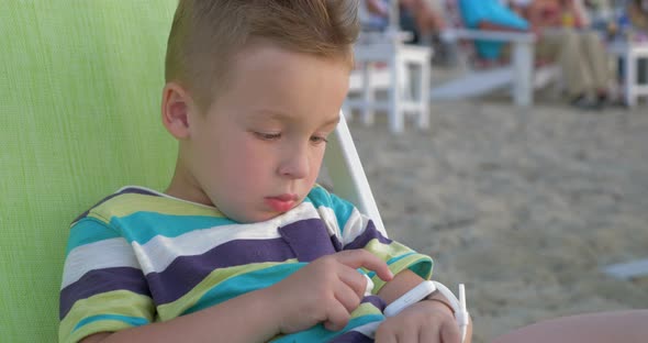 Little boy with smart watch sitting in deck chair