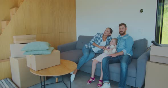Moving, People, Repair and Real Estate Concept - Happy Family with Big Cardboard Boxes on Sofa at