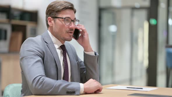 Cheerful Businessman Talking on Smartphone in Office
