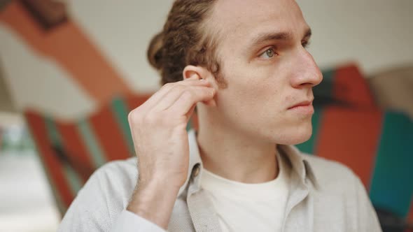 Concentrated curly-haired man putting on headphones