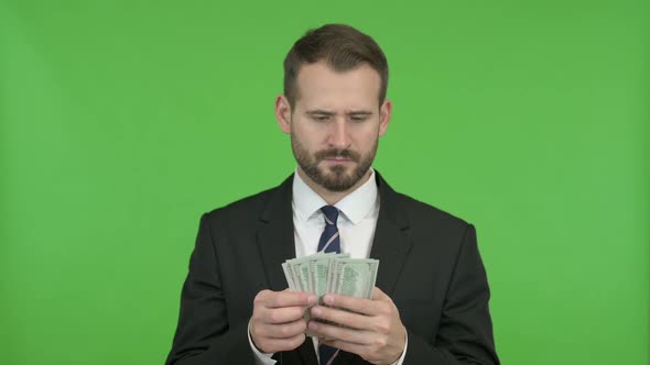 Young Businessman Counting and Offering Money Against Chroma Key