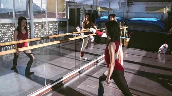 Young dancers training together in studio warming up and flexing in sunlight