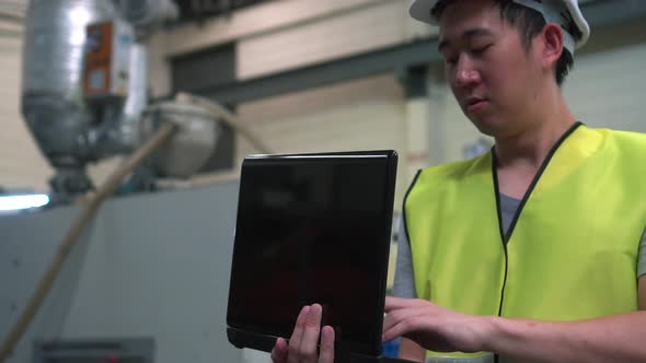 Industrial Engineer with Hard Hat Working with Laptop at Factory