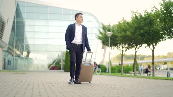 Asian tourist businessman walks public transport building with luggage on the urban 