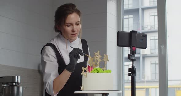 A Professional Confectioner Conducts a Master Class Telling and Showing How to Decorate a Dessert