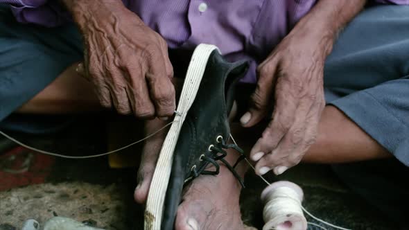 A cobbler repairing slippers of pilgrims by the roadside in the morning stock footage collection 18