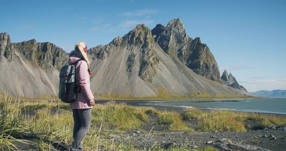Woman Enjoying Costline with Black Sand Beach in Stokksnes and Vestrahorn Mountain in the Background