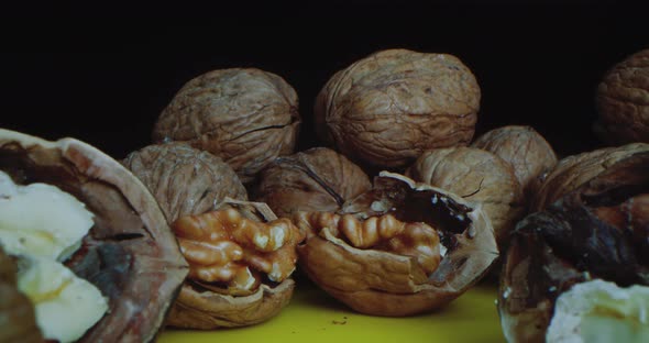 Closeup Shot of Walnuts Which Lie on a Yellow Table Against a Black Background