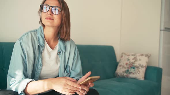 Close Up Shot of a Young Adult Woman in Glasses Using Her Smartphone