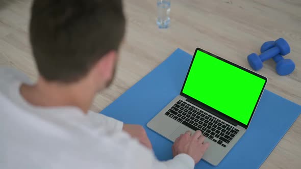 Rear View of Man Doing Yoga While Looking at Laptop with Chroma Key Screen